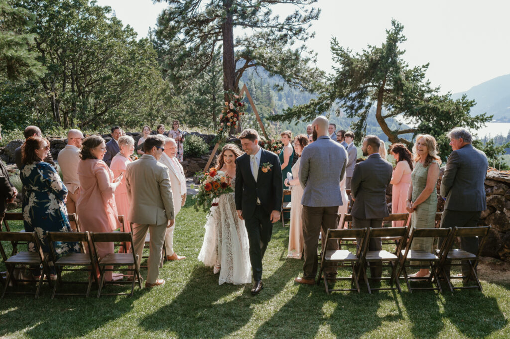 bride and groom smiling and walking down the aisle during their recessional 