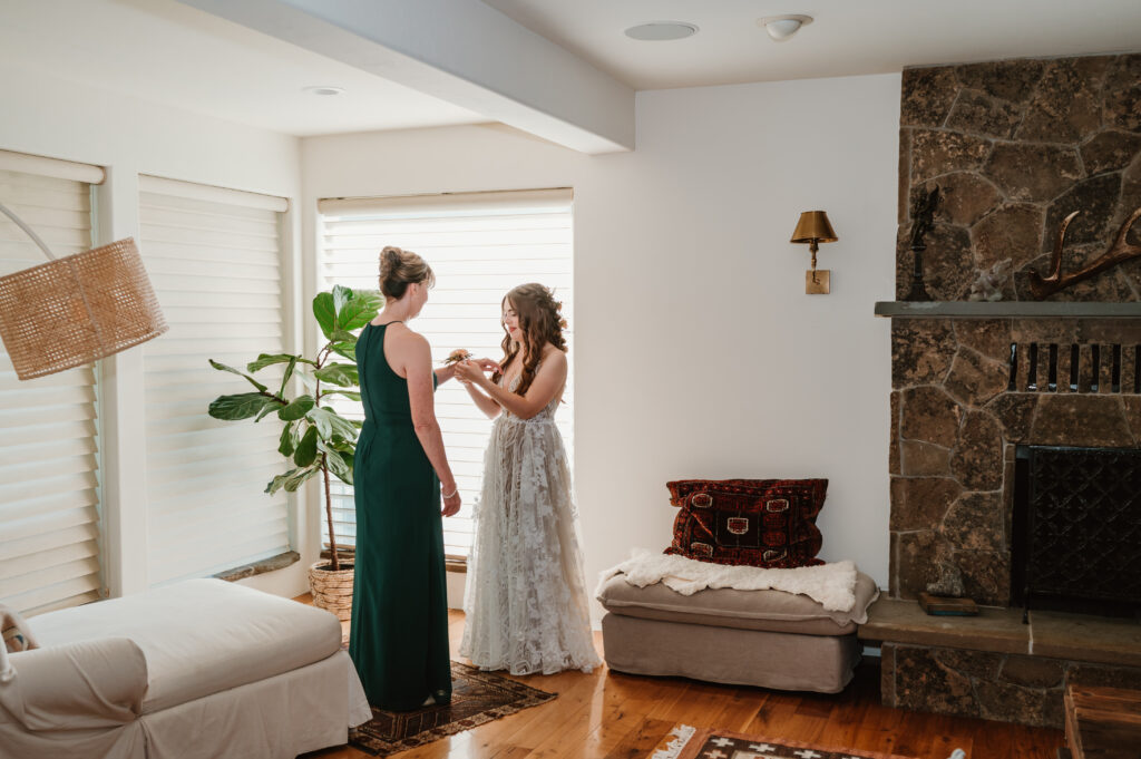 bride helping mother in law getting wedding corsage on