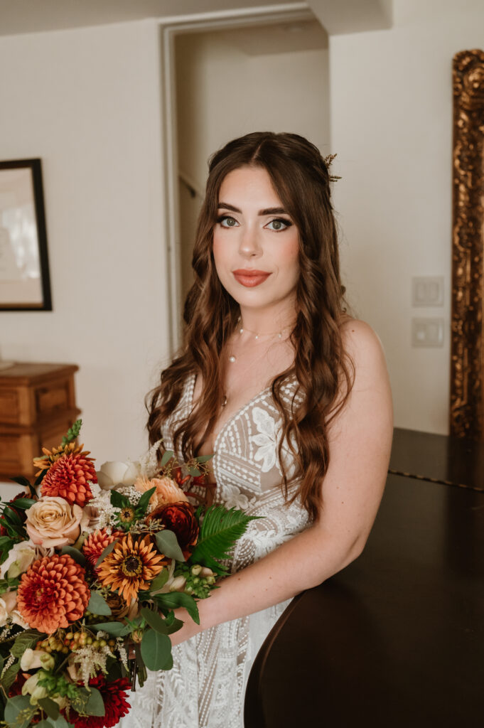 bride with her bridal bouquet leaning against the piano 