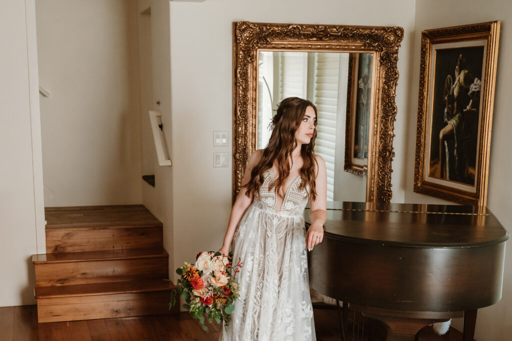 lace bridal gown and bride leaning against piano 