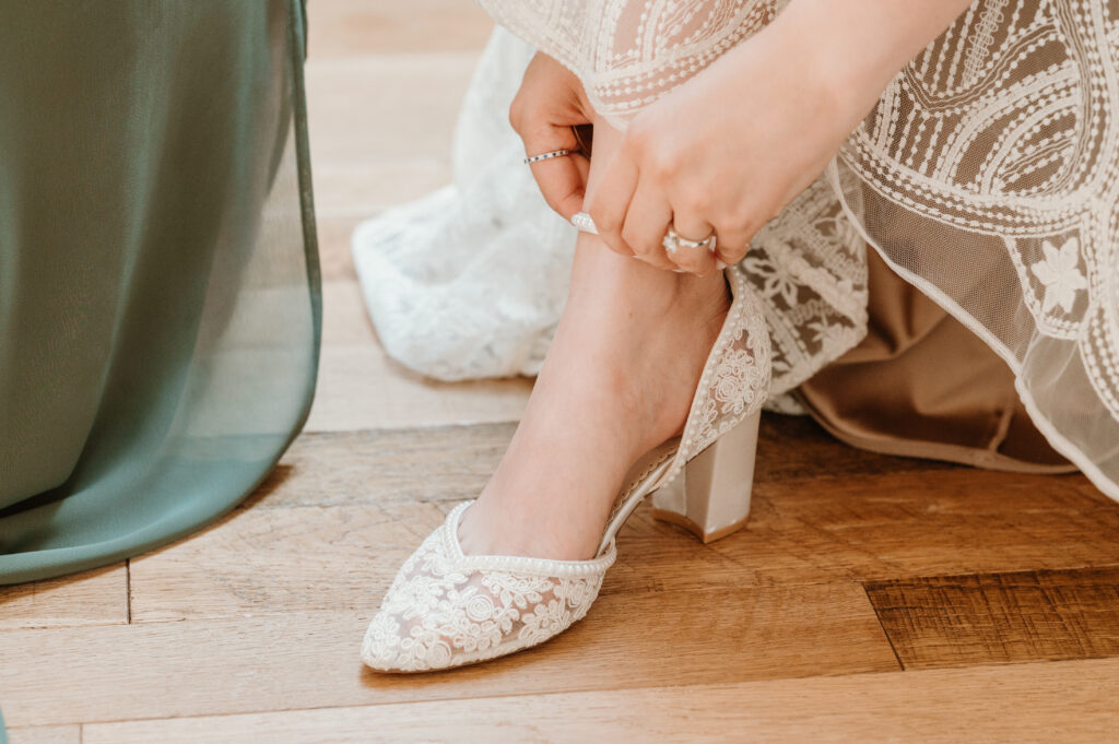 bride putting on lace shoes