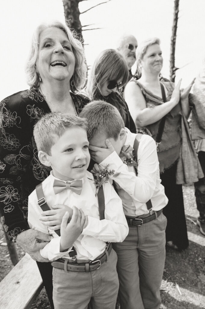 kids of bride and groom hiding their eyes and smiling as bride and groom share their first kiss 