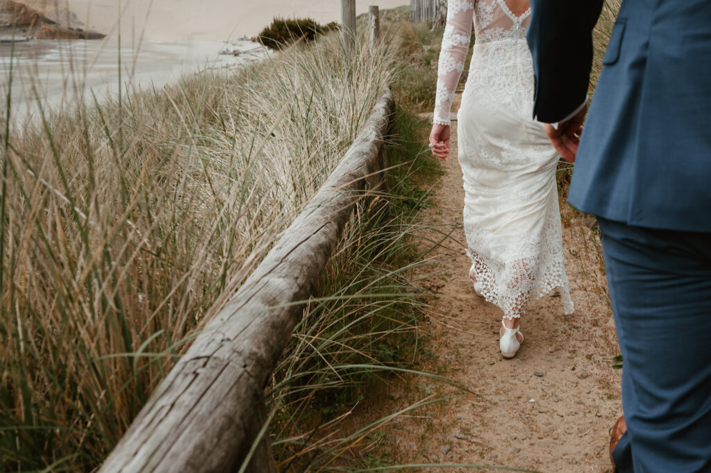 bride and groom walking together to their next location at their oregon coast wedding 