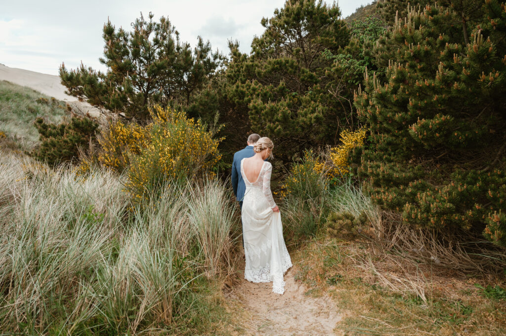 Bride and groom walking on a trail at Cape Kiwanda for their intimate coastal wedding 
