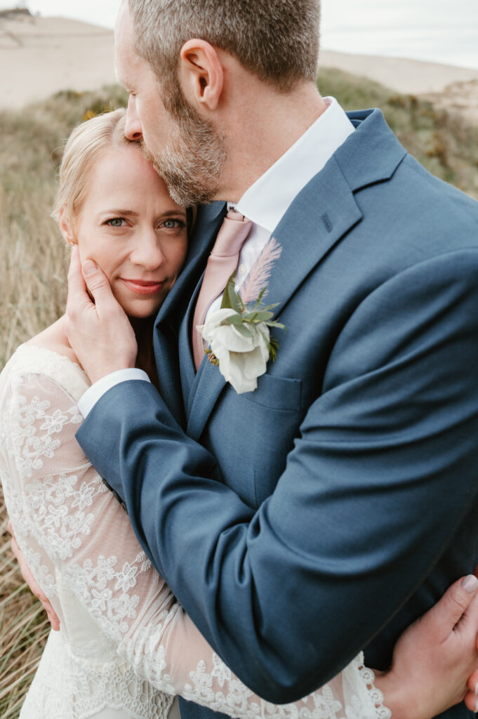 Groom holding bride and kissing her forehead at their intimate oregon wedding 