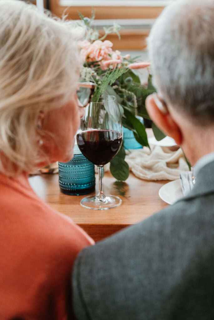 close up of a wine glass through the view of a couple sitting at a table at an oregon coast wedding 

