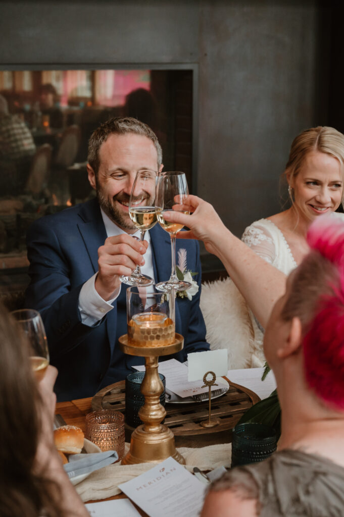 Groom and his sister clinking their glasses together in a cheers 