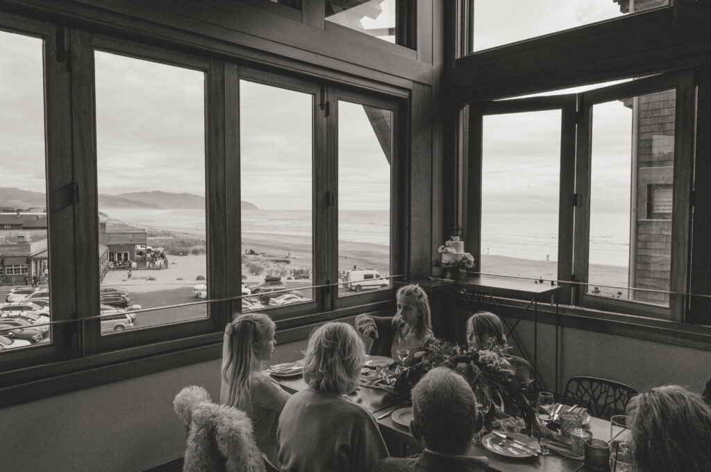 family sitting at the reception table with a view of the ocean at this intimate oregon coast wedding 